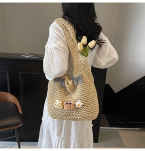 Gros plan du sac cabas en paille avec nœuds mignons et breloques ours en peluche