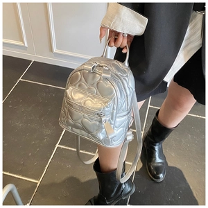 Detail of silver heart-quilted mini backpack with metallic zippers and top handle