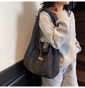 Detailed view of the dark grey denim tote bag featuring a leather logo and drawstring bow