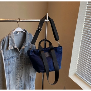 Détail du grand sac cabas en denim bleu foncé avec poignées en toile et logo en cuir