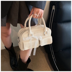 Detail of cream Boston bag with delicate lace bow and functional front pockets