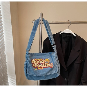 Detail of blue denim messenger bag with vintage embroidery and adjustable strap