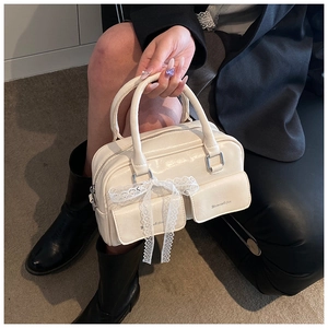 Close-up of cream PU leather handbag with lace bow detail and dual front pockets