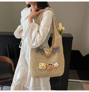Détail du sac cabas en paille tissé avec nœud mignon et patchs d'ours sur robe blanche