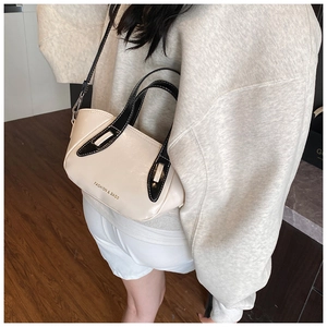 Close-up of cream crossbody bag with black contrast trim and white stitching detail