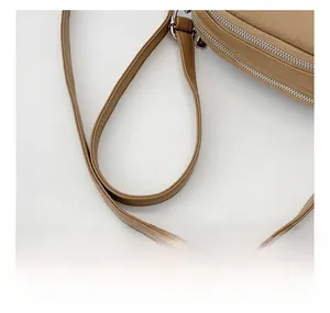 Detail of adjustable shoulder strap and silver metal buckles on a khaki crossbody bag