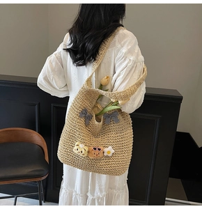 Détail du sac cabas en paille avec nœuds vichy et breloques ours en peluche sur l'épaule