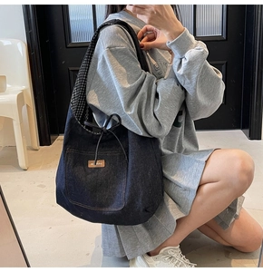Detail of dark blue denim tote bag with leather patch pocket and drawstring closure