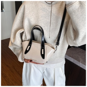 Detailed view of the cream crossbody bucket bag with black handles and metal buckles