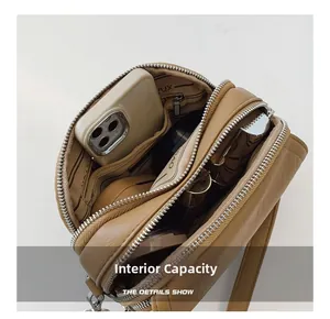 Close-up of three-layer zipper compartments in a khaki crossbody bag for organization