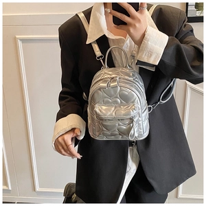 Mirror selfie showing a silver mini heart-quilted backpack with metallic finish