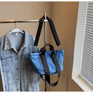 Détail du sac cabas en denim bleu avec anses en nylon noir et ferrures en métal