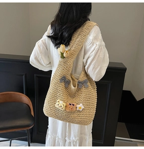 Détail du sac cabas en paille tressée avec nœuds mignons et breloques d'ours en peluche