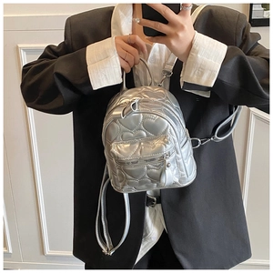 Close-up of silver mini backpack featuring quilted heart patterns and metallic finish