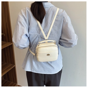 Dettaglio del piccolo zaino multifunzionale in pelle PU bianco crema con logo tondo in metallo