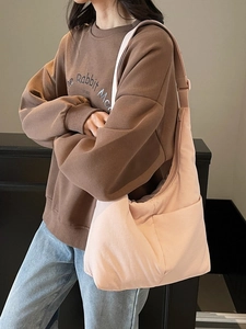 Pink crescent nylon tote bag with wide strap worn by model in casual lifestyle setting