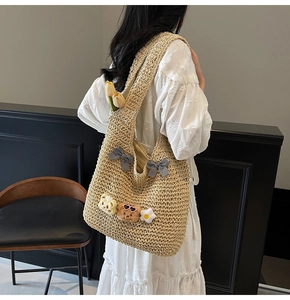 Détail du sac cabas en paille tissée avec nœuds noir et blanc et pendentifs en peluche