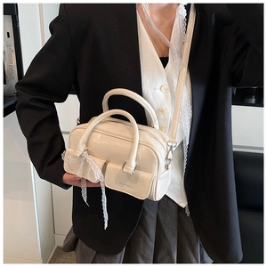 Detail of cream Boston bag featuring lace bow accent and dual front utility pockets
