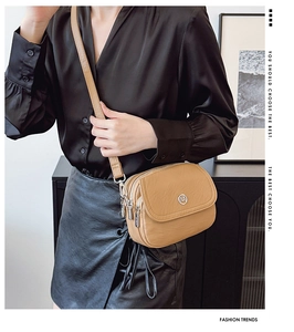 Three-layer khaki faux leather crossbody bag with silver hardware on a black shirt model