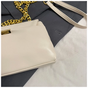 Close-up of cream square bag with gold chain strap and textured leather finish