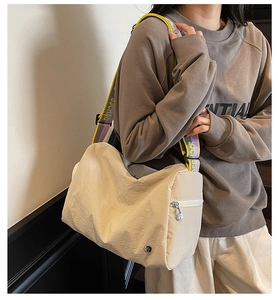 Detail of beige nylon crossbody bag with wide colorful jacquard strap and metal logo
