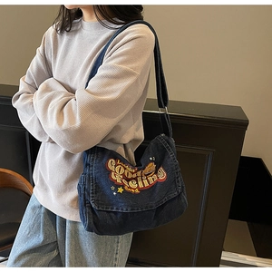 Detail of colorful embroidery and star pattern on dark blue denim crossbody messenger bag