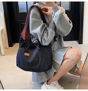 Close-up of denim tote bag featuring red checkered lining and brown leather patch detail
