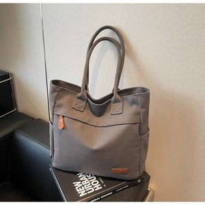 Detail of dark grey canvas tote bag with leather buckle pocket and side compartment