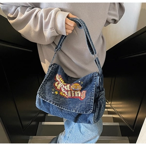 Detail of blue denim shoulder bag featuring Feeling Good star embroidery and wide strap