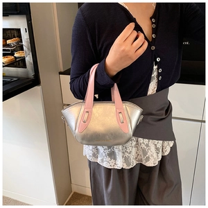 Close-up of metallic silver mini handbag with pink handle and branded lettering