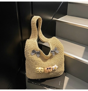 Détail du sac cabas en paille avec des nœuds à carreaux et des breloques en peluche