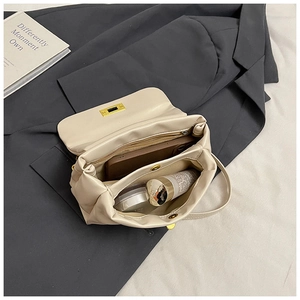Detailed interior of creamy white pleated crossbody bag showing dual compartments and gold lock