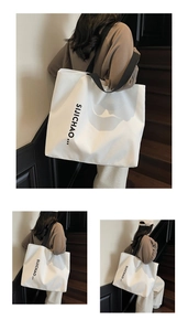 Detail of white tote bag with black letter print and wide strap for daily use