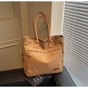 Detailed macro view of khaki canvas tote bag featuring leather zipper pull and side pockets