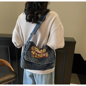 Detail of blue denim crossbody bag with colorful Good Feeling embroidery and strap