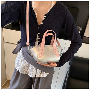 Silver metallic bucket bag with pink handles worn by a model in a minimalist setting