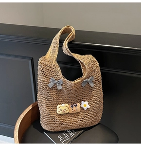 Détail du sac cabas en paille tressée avec des nœuds mignons et breloques d'oursons