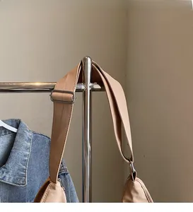 Detail of adjustable wide shoulder strap and silver metal buckle on khaki nylon tote bag