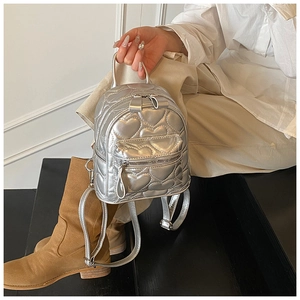 Detail of silver mini backpack featuring heart-shaped quilting and metallic leather texture