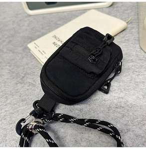 Detail of black mini nylon bag showing double zippers and adjustable woven lanyard cord