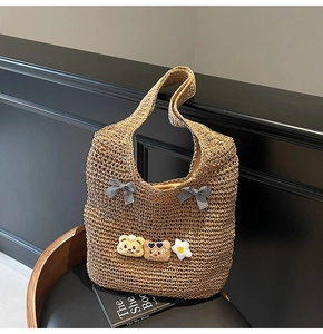 Détail du sac cabas en paille tissée avec nœuds à carreaux et breloques ours en peluche
