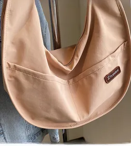 Close-up of beige nylon crescent bag featuring large side pocket and Ziyouse brand label