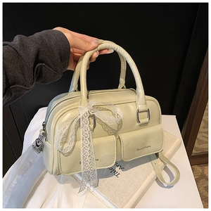 Close-up of light green handbag with twin pockets, lace bow detail and textured faux leather