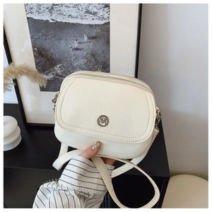Detail view of cream white PU leather crossbody bag featuring dual zippers and metal logo