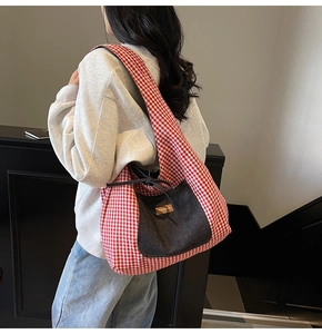 Macro shot of large canvas tote bag featuring red striped patterns and denim front pocket