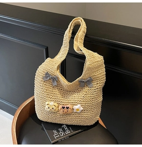 Détail du sac cabas en paille beige avec nœuds à carreaux et breloques ours peluche