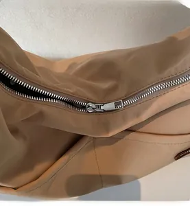 Close-up of smooth silver metal zipper on khaki nylon tote bag showing detailed texture