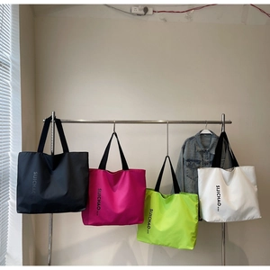 Detailed row of tote bags in black, pink, green, and white with vertical typography