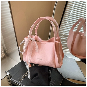 Detailed view of pink pebble leather handbag with elegant white lace bow on the handle