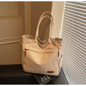 Close-up of beige canvas tote bag detailing leather accents and durable fabric texture